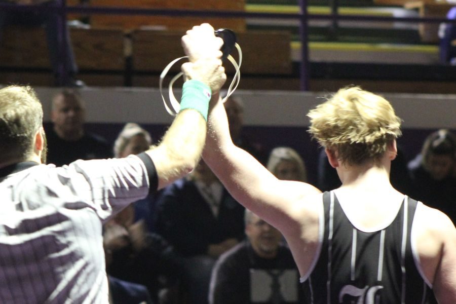 The referee raises Caleb Coverts fist in victory in a match against Eureka.