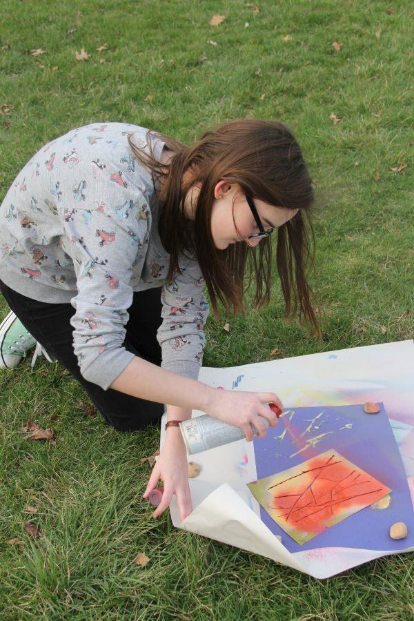 Participating in Art of Life’s spraypaint day, Caroline Karsten, junior, spray paints a stencil over a sheet of construction paper. Art of Life is a club made up of artists that get together to create art with unique materials. “I really liked using the spray paint because there are just so many things you can do with it and you can get a lot of different effects with them,” Karsten said.