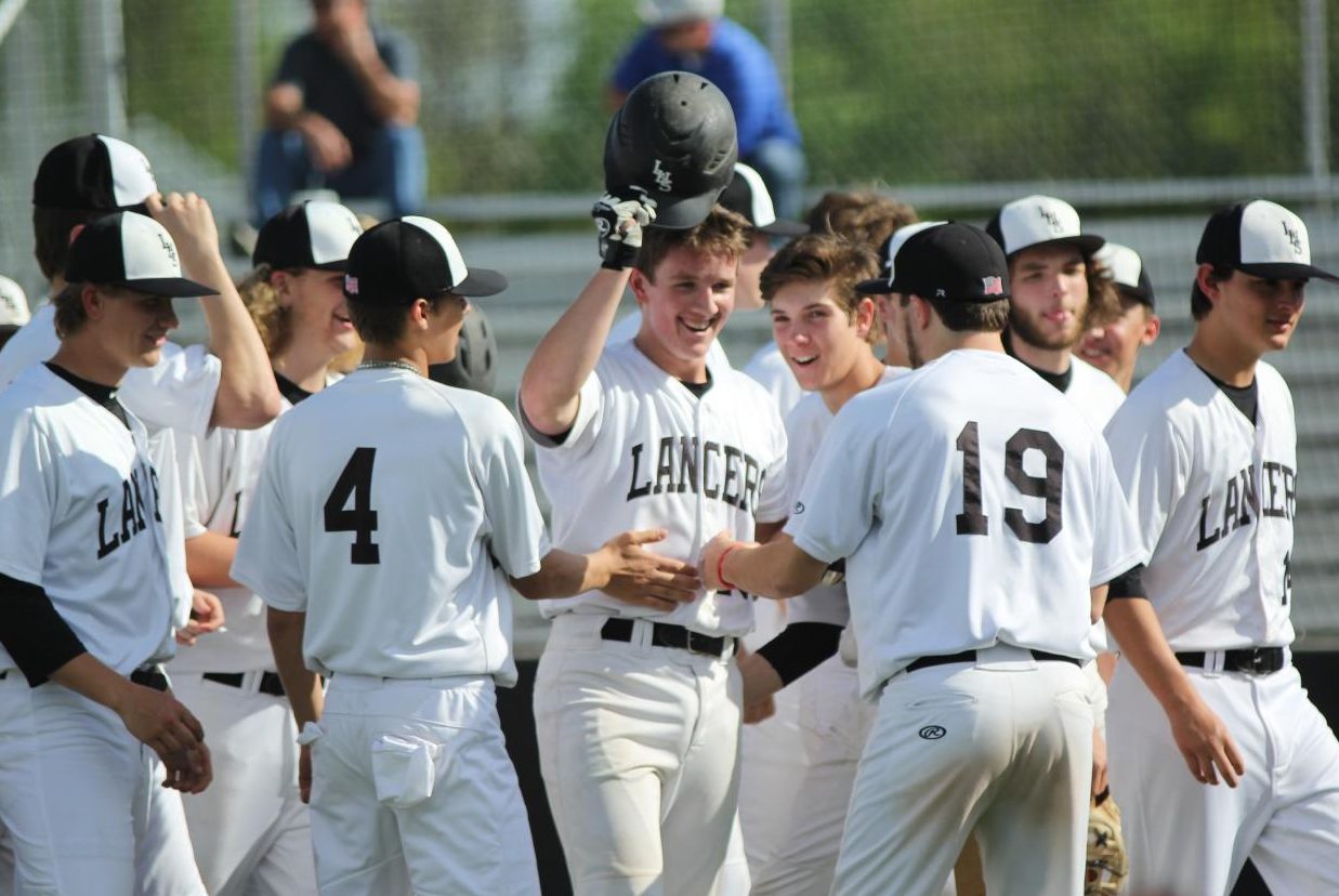 After hitting it out of the park, teammates gather around Wade Stauss to celebrate his home run.