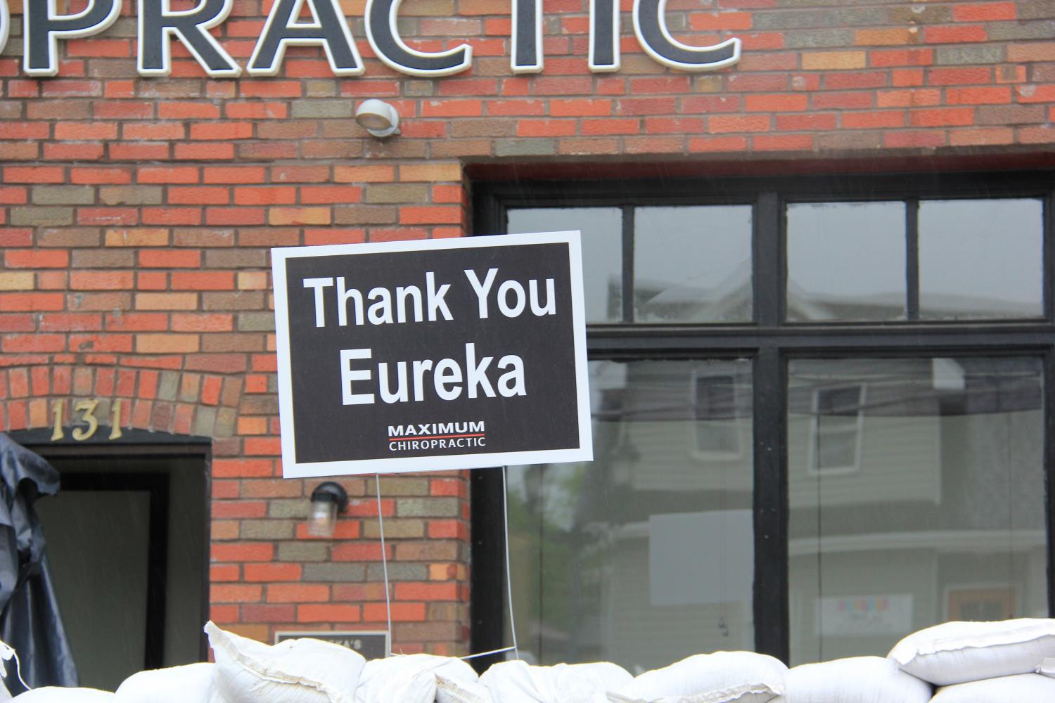 A sign reading Thank You Eureka is posted on top of a wall of sandbags in front of Maximum Chiropractic as water flows down South Central Avenue in Downtown Eureka.