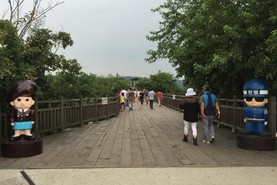 Visitors walk across a bridge in South Korea that borders North Korea. The entrance to the bridge is flanked by North Korean (left) and South Korean (right) soldier figurines.