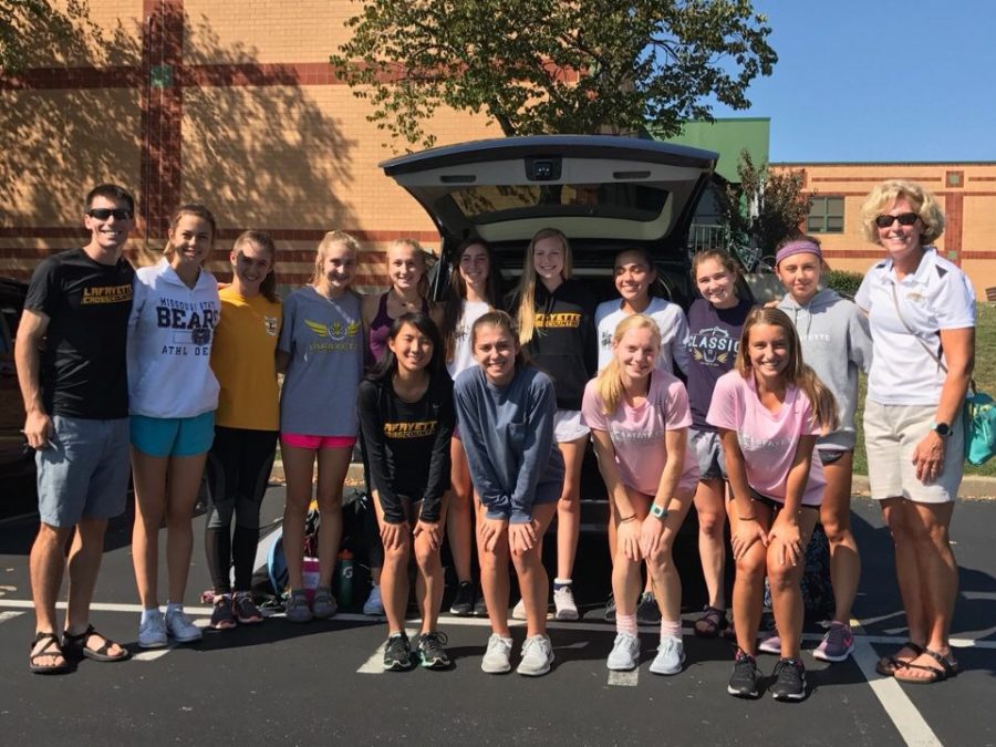 Before traveling to Lawrence, KS, the girls cross country team poses for a picture in front of their rented van. Girls varsity placed 32nd as a team in the substantial race.