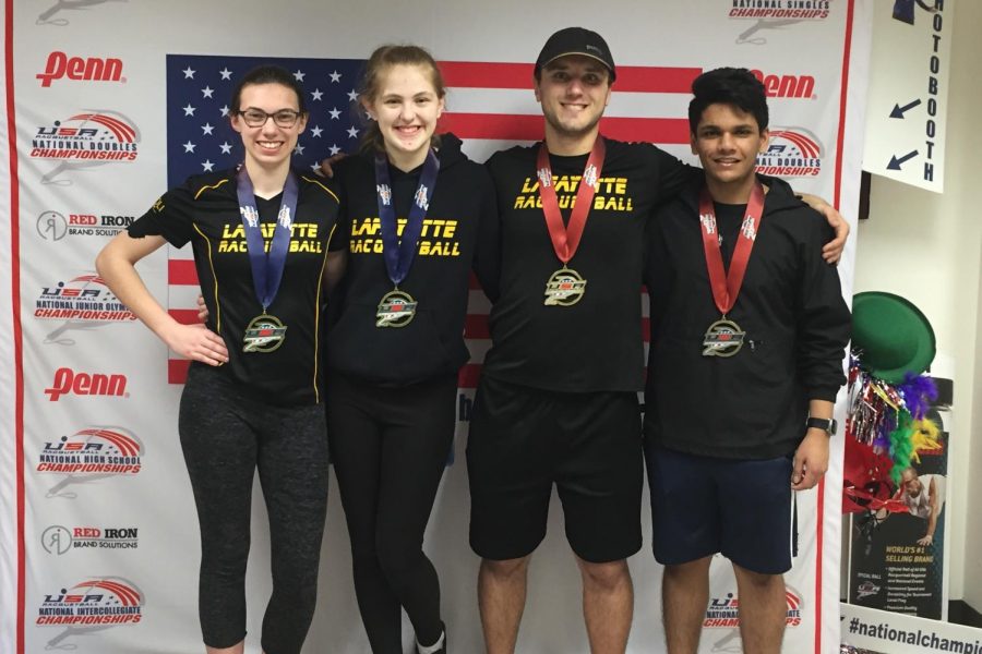 After+the+finalist+matches+finished%2C+seniors+Kate+Buren%2C+Allyson+Howard%2C+Jakob+Molskness+and+Shlok+Natarajan+pose+in+front+of+the+USA+Racquetball+National+Championships+sign.+They+all+won+medals.++