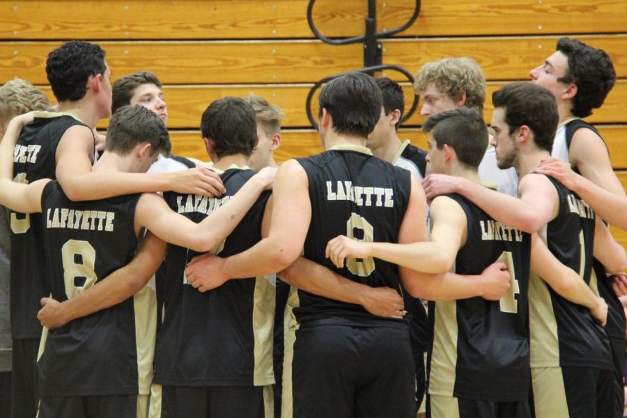 The boys volleyball team huddles together to discuss a game plan. 