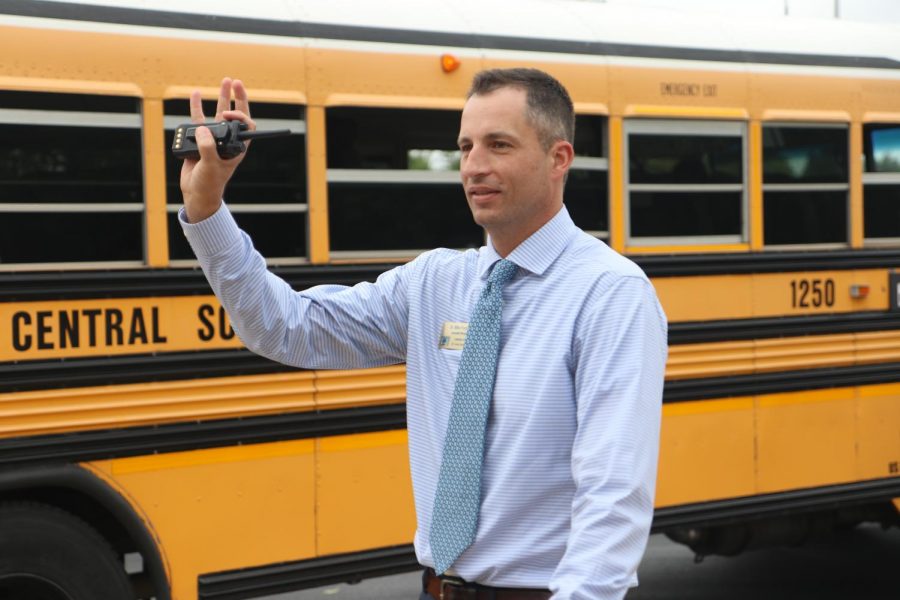 Completing his afternoon dismissal duties, Dr. Michael Franklin, associate principal, waves at departing buses.