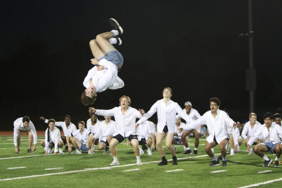 As eyes everywhere locked on to him, Connor McCool, senior, flies through the air during Male Escadrilles performance at halftime of the Powderpuff game on Thursday, Sept. 27. Male Escadrille performed once again the following day at the Homecoming Pep Assembly. I was nervous because the turf was wet and I thought I was going to slip. It was kind of freaky on the first flip when everyone started cheering, McCool said.