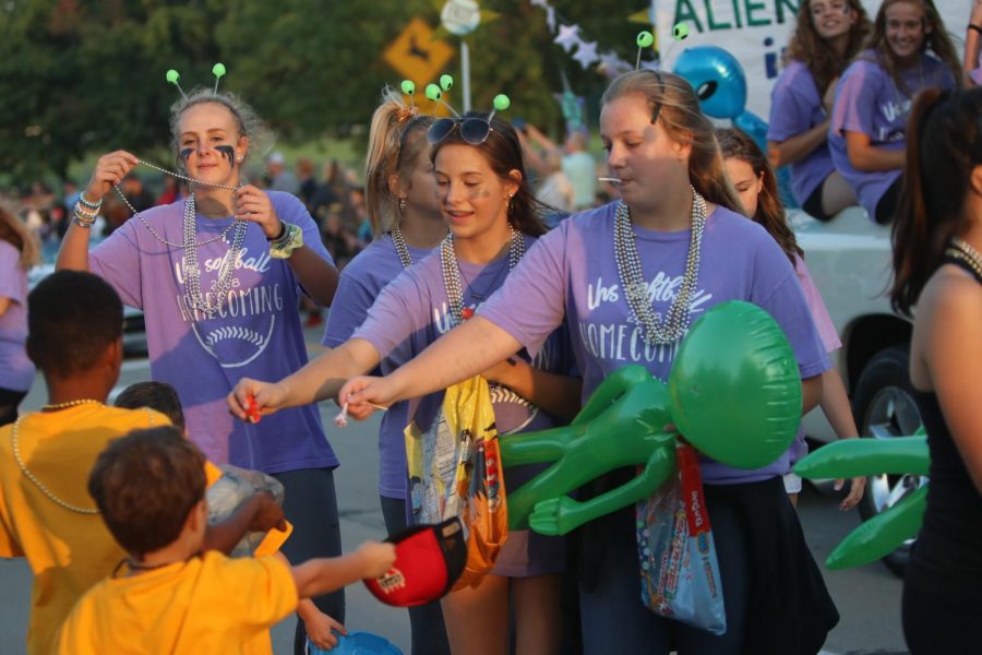 Junior Maddie Chester and other girls hand out candy on the softball float during the Homecoming parade.