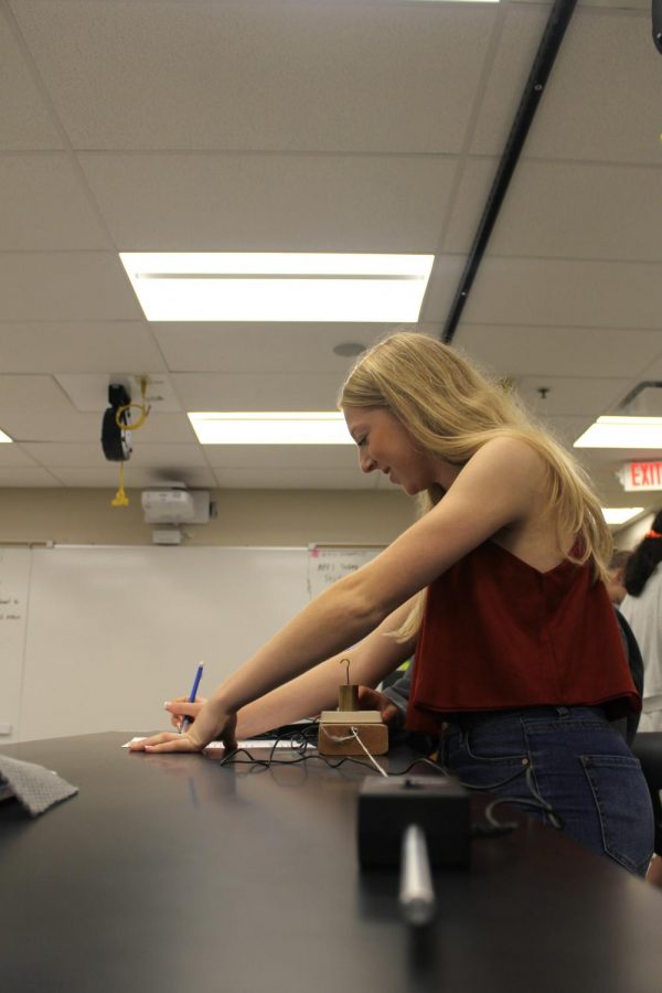 Nicole Lawson, senior, records her results during an AP Physics lab about static and kinetic friction. 
