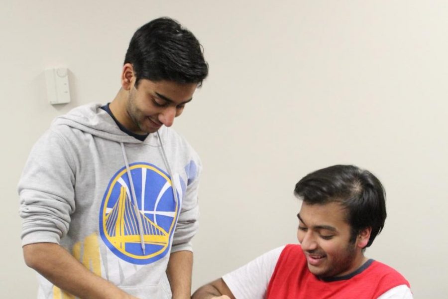 Seniors Rishi Ray and Maurya Akula apply pressure to a pool noodle to learn about proper methods to stop bleeding.