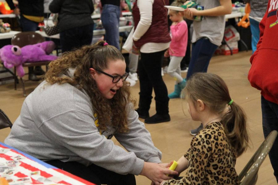 Applying a temporary tattoo on the arm of a child, Hannah Molskness, senior, volenteers at the Winter Carnival on Jan. 26. 