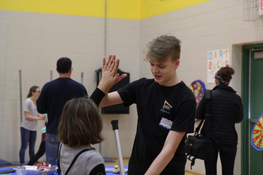 Joshua Zhuchenik, sophomore, gives kids high fives while volunteering at the Hockey booth. 