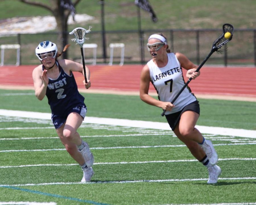 Running up the field in the April 6 game against Lees Summit West, senior Katherine Goddin looks to pass the ball. In the win 11-3, Goddin scored 8 goals to become the leading scorer in the St. Louis area with 37 goals and 47 points. 