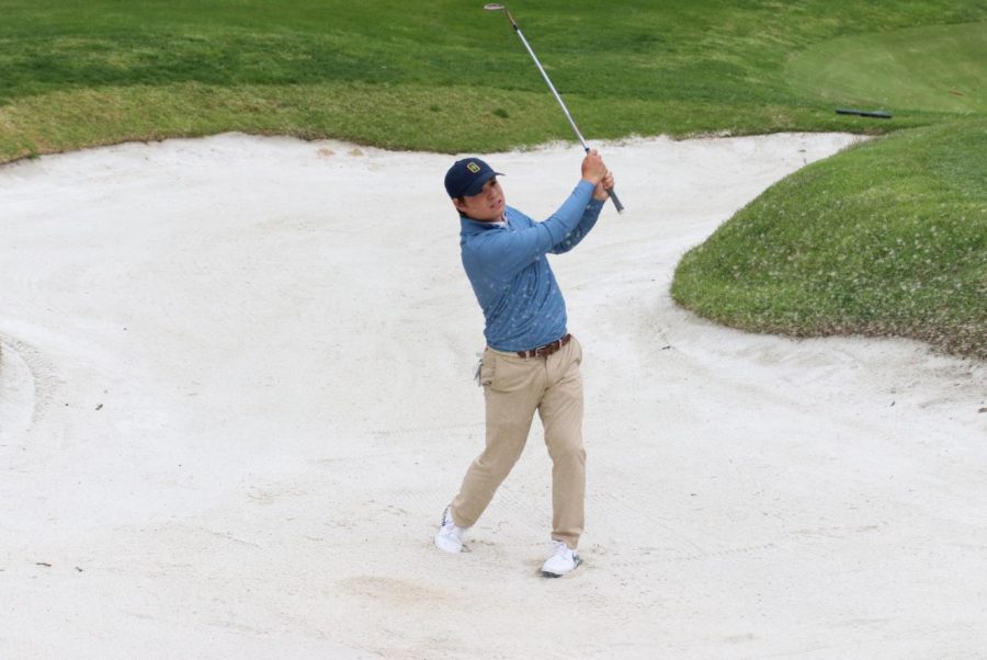 While preparing for a golf match, senior Max Kreikemeier attempts to get our of a sand trap.