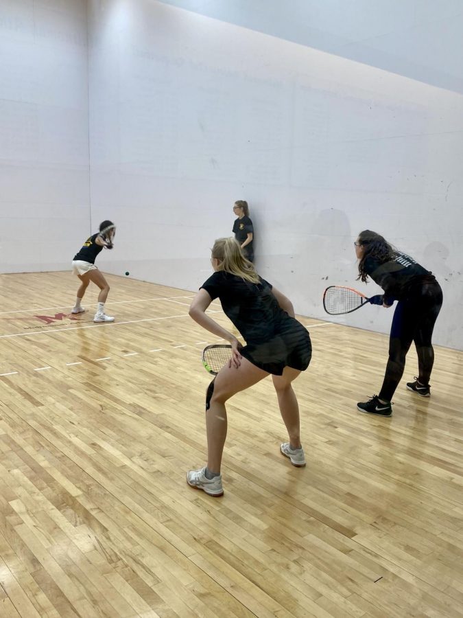 Doubles partners sophomores Kyla Davis and Anna Matusiak (back-left to right) crouch in ready position as Gresham, Oregons Barlow racquetball serves the ball to Daviss backhand. Davis feels confident in her backhand, she said that, that is her go-to position while playing doubles. 