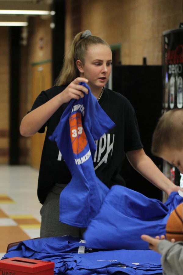 As she checks teams in for the tournament, NHS Executive Board member Madison Chester, senior, passes out shirts. Each of the 35 tournament participants received a shirt for playing. 