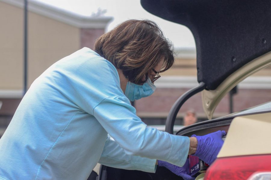 On March 18, a woman loads up her car after shopping at Walmart. As a precaution, she wore gloves and a mask in order to delay the transmission of COVID-19.