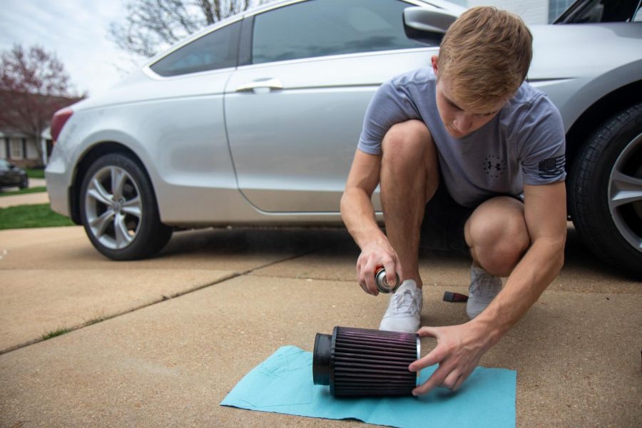 Senior Jake Dederer sprays oil on his cold air intake after cleaning it to pass time while self-quarantined at home, March 27.