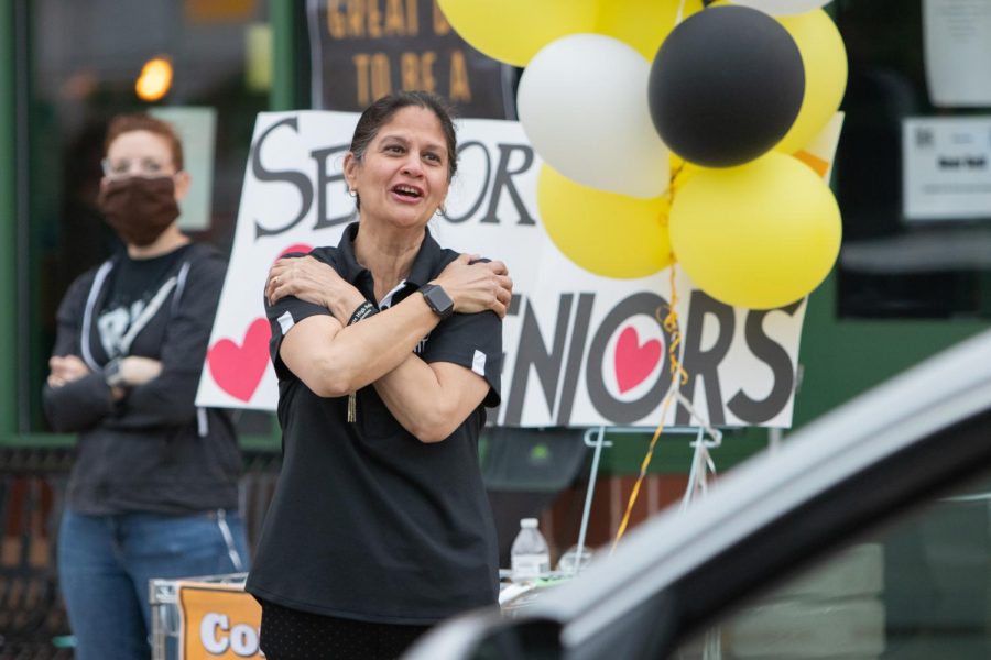 Watching as seniors leave the parking lot, Assistant Principal Kirti Mehrotra gives air hugs at the farewell parade held for the Class of 2020 on May 21.