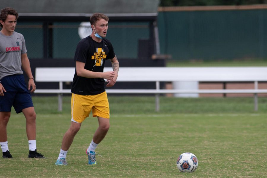 In a practice, boys soccer Head Coach Ryan Butchart demonstrates a play that his team needs to execute. Soccer falls in the medium sport contact, and has now moved on to more active drills and scrimmages at practice.