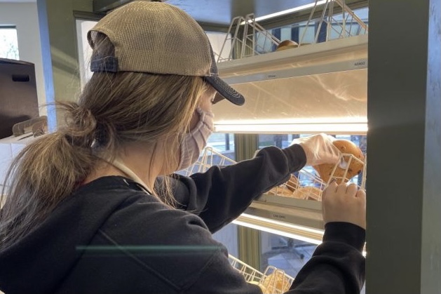 Junior Marissa Trottier restocks bagels during her morning shift at St. Louis Bread Company.