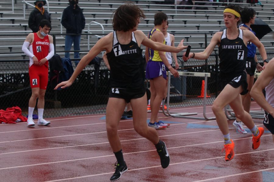 On a rainy morning at the Lafayette Track and Field Invitational,  junior Bross Miller passes the baton to senior Noah Kronauge in the 4x800 relay.