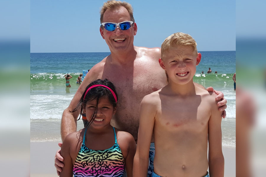 Freshman Annie Jones smiles with her father, Tim Jones, and her brother, Matthew Jones, on a beach in Florida on a family vacation. November is National Adoption Month, which was established to raise awareness for children in the foster system looking to be adopted.