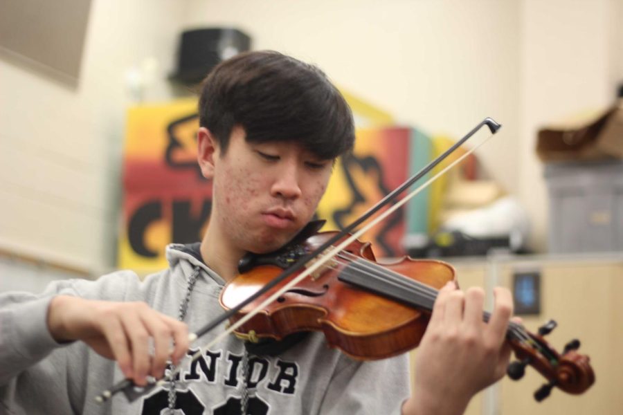 Senior Darren Hwang plays his violin in the symphonic orchestra classroom. 