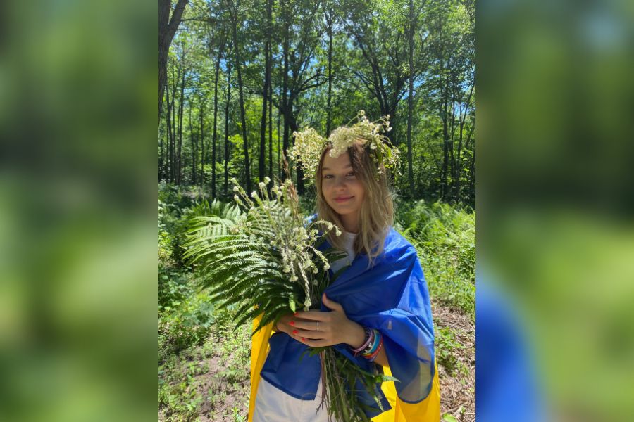 Wrapped in the Ukrainian flag, freshman Leeza Nozdrachova holds plants and flowers for Ivana Kupala, a Slavic holiday celebrating the summer solstice.