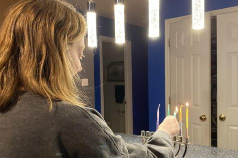 Junior Taylor Lefkowitz lights the third candle in her Menorah. Menorahs held nine candles, and each night, during Hanukkah, a new candle got lit.