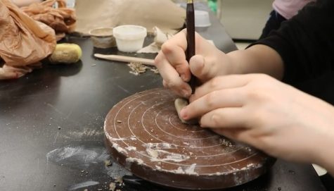 Junior Elizabeth Hanson sculpts the details on her frog during Ceramics class 1st Hour.