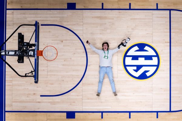 On the hardwood court of Bridgestone Arena in Nashville, Tennessee, Class of 2020 alumni Jack Weaver lays on the court, camera in hand. Weaver has had the opportunity to shoot photos for University of Kentucky games as a member of the Kentucky Kernel. 