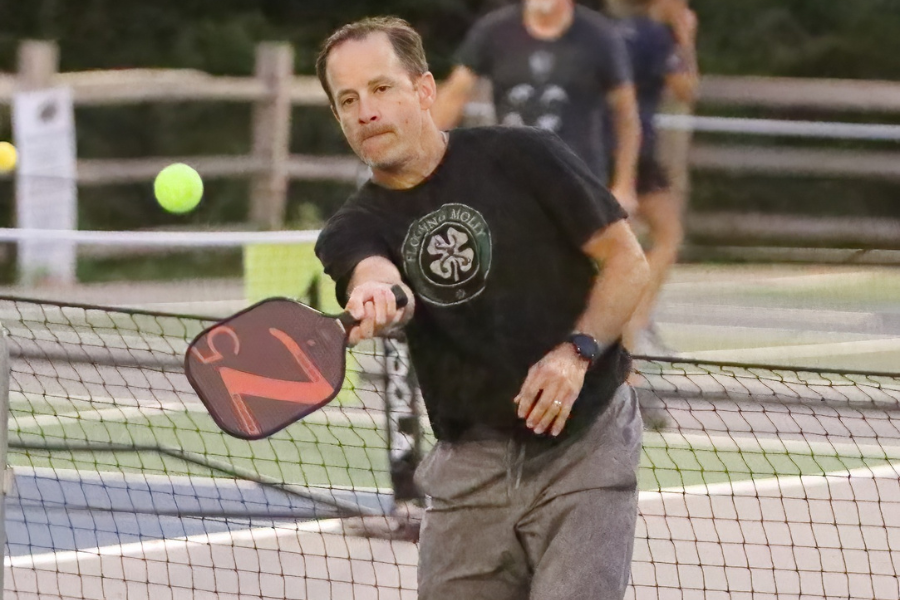 At the baseline, math teacher Jason Schneider swings his paddle to return a volley. Schneider has started a staff pickleball group at Lafayette for those interested in playing. 