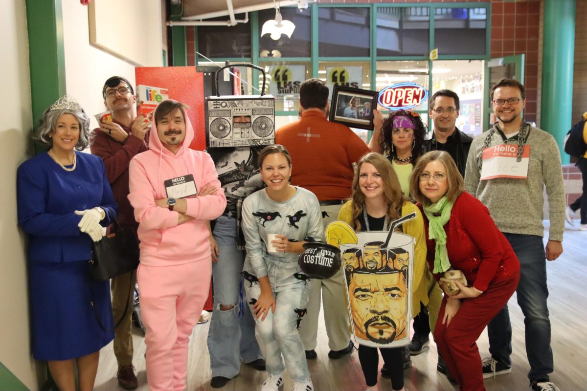 Showing off their trophy, the Fine Arts Department poses for a photo after winning the Staff Halloween Costume Contest. After other staff members and departments displayed their costumes the Fine Arts Department came out on top, taking the win. 