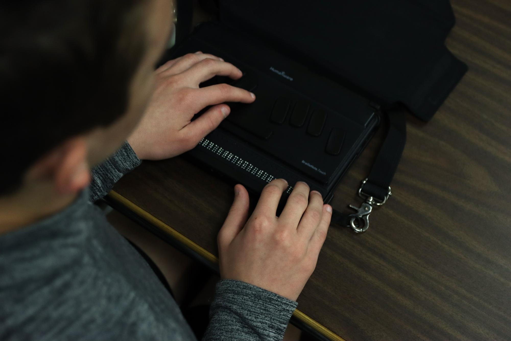 In AcLab, freshman Max Ottinger types his notes on a BrailleNote. SSD teacher Laura Beckhard reads to him from the textbook so he can transfer the notes.