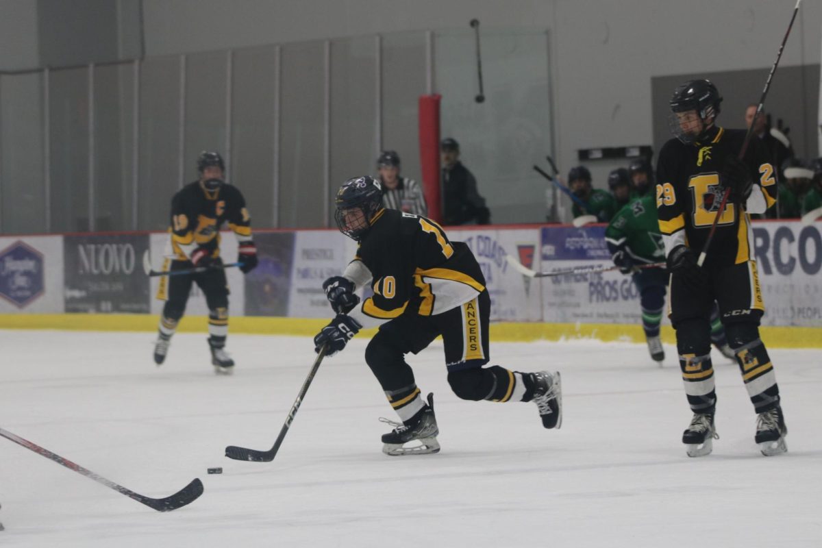Gliding down the rink, senior Greyson Eble lunges for the puck. Eble has scored seven goals in the seven games played this season.