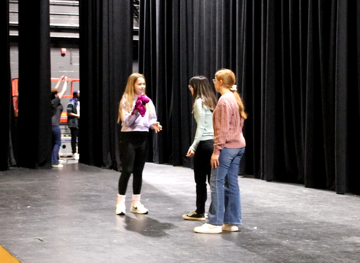 Actors Keira Makalintal, Lizzie Rattenborg and Rylee Stoffell perform a scene onstage.
