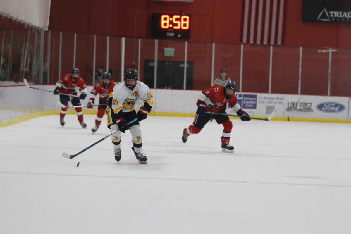 Gliding down the ice, senior Greyson Eble leads a fast break against Priory in their first round-robin game. Eble scored a hat trick in their last round-robin match against Seckman. The Lancers will play their Fox Feb. 13.