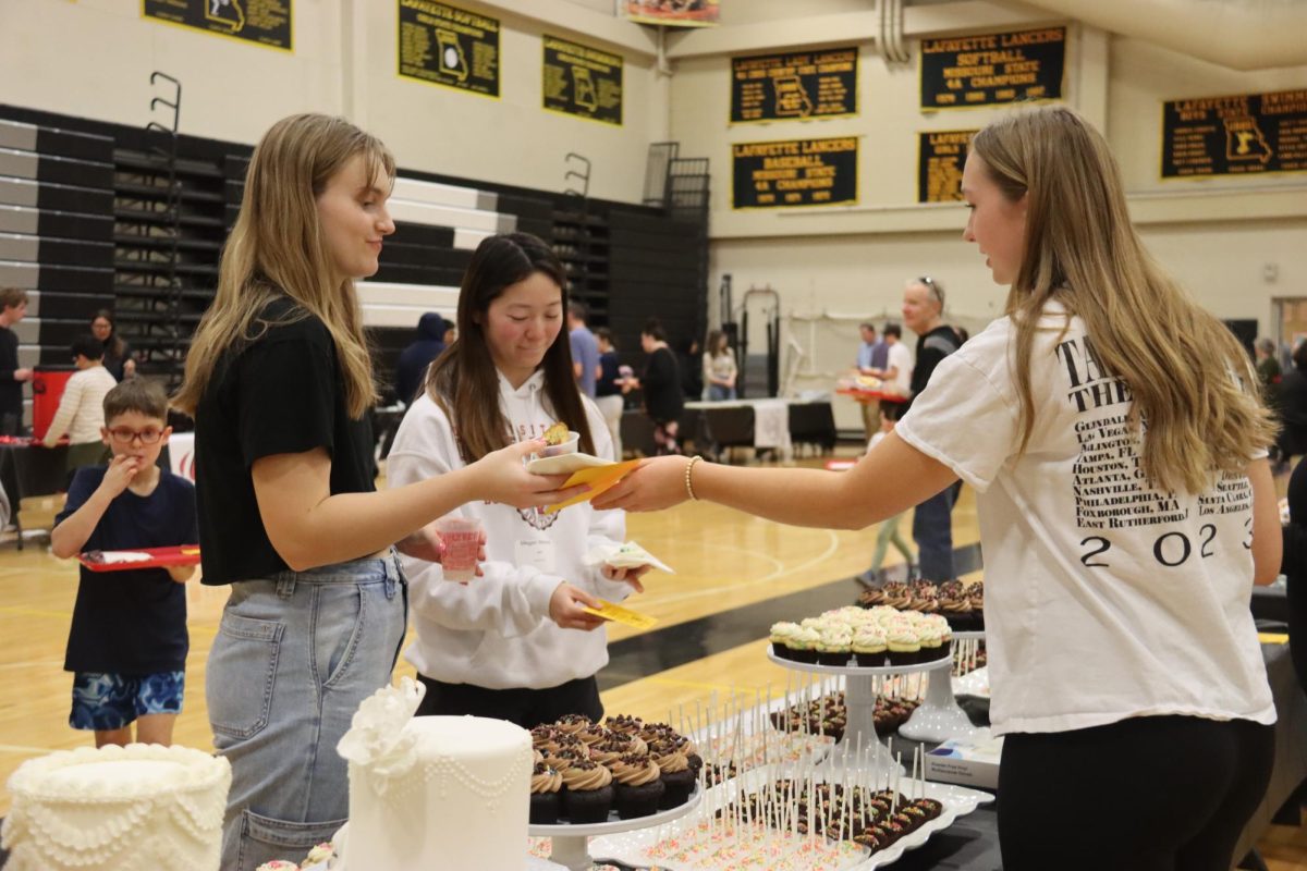 At Lafayette High School, Lauren Dean hands Caroline Trost and Megan Bilsland a sweet treat from the Sarahs Cake Shop booth at the Taste of West County to help raise money for the Junior Class.