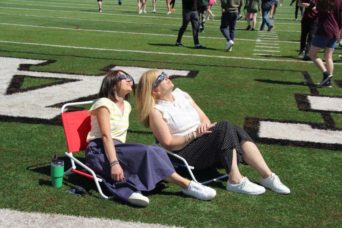On April 8, during the eclipse, librarians, Jane Lingafelter and Robin Van Iwaarden, look at the sun using solar viewers, while on the field. Students and staff spent time on the field during the eclipse. The next partial eclipse in Missouri wont be till 2045.
