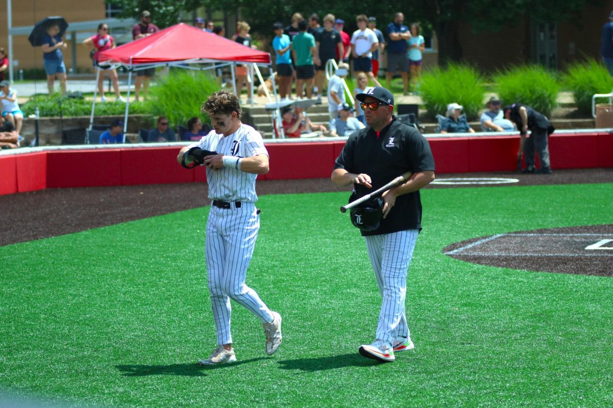 Don Kreienkamp, Varsity baseball Assistant Coach, and Junior Michael Callahan walk together at the District Final game May 18. The Lancers won the game 3-1 and became District Champions.