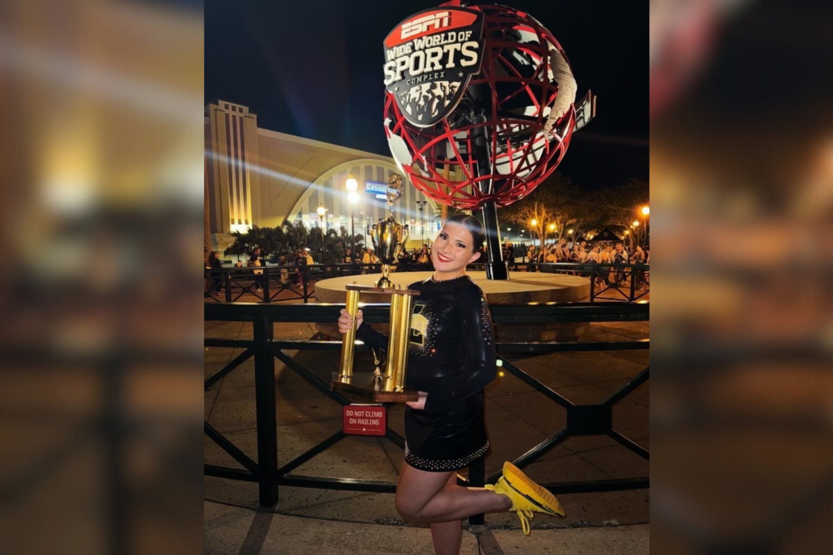 After receiving 7th place at Nationals with Varsity Escadrille, Raymond poses with the trophy in front of the ESPN World Wide of Sports Complex globe. I felt a rush of everything. All the feelings, all the hard work just rushed through my body, Raymond said.