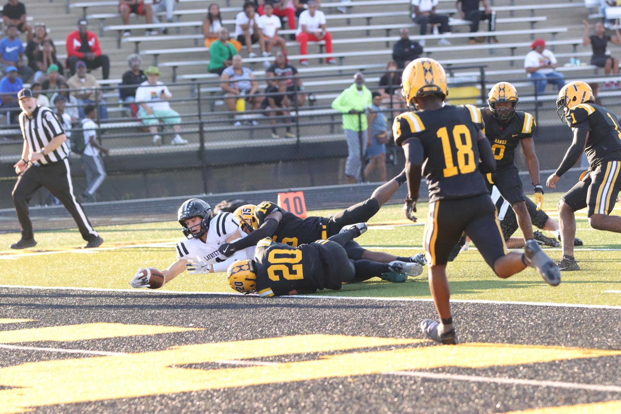 As he is tackled by two hawks, wide receiver Robby Preckel scores a touchdown.