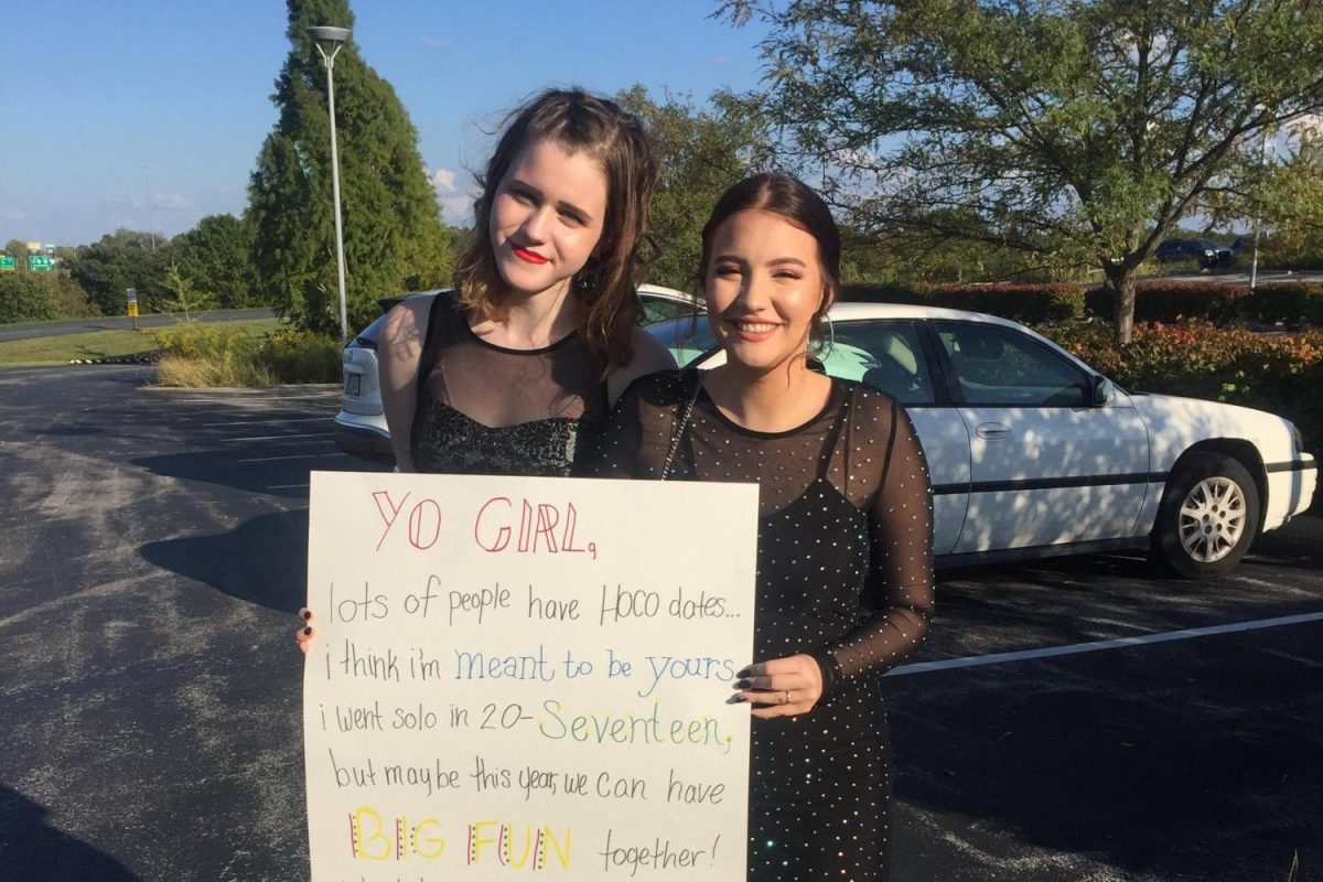 Language arts teacher Cat Hill (left) asks her best friend to a homecoming dance with a poster. The poster references songs from the musical, Heathers by Kevin Murphy.