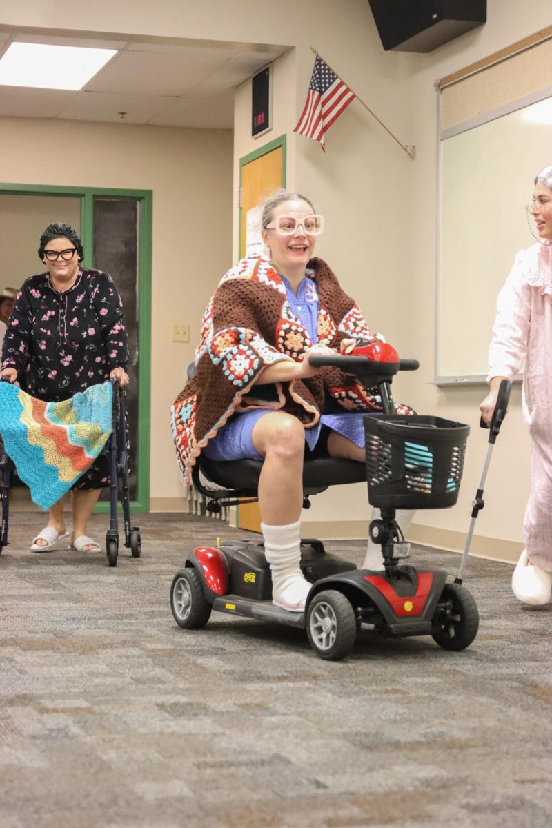 Zooming past her fellow FACS teachers, Lauren Arnet rides a mobility scooter across the room.