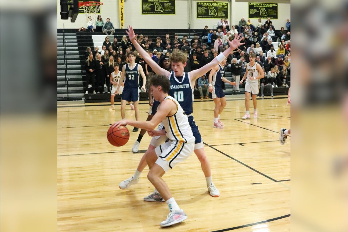 Junior guard Nolan Savoie dribbles around Marquette defender. The Lancers finished this game losing 42-61.