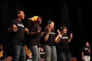 A team consisting of seniors Ella Luvai and Raymond Murphy-Cazembe, junior Mary Kirtley and sophomore Luke Matheus introduce themselves to the crowd as "Time Flies" while flapping their hands on Friday, Apr. 25. The performance was Undefined's last improv show of the 2024-2025 school year.