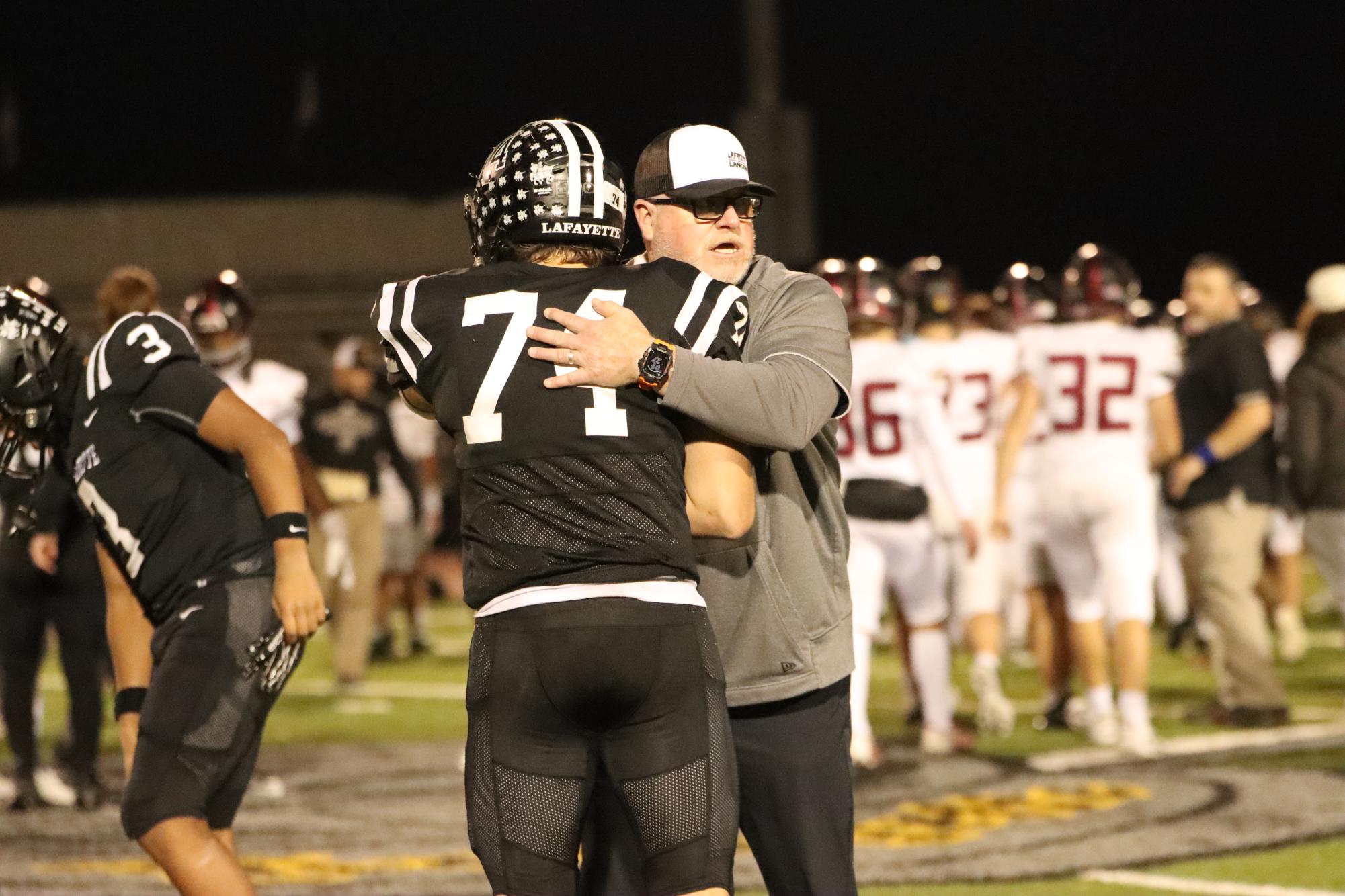 Under the lights, Coach Boyd Manne and junior defensive lineman Noah Ice embrace.