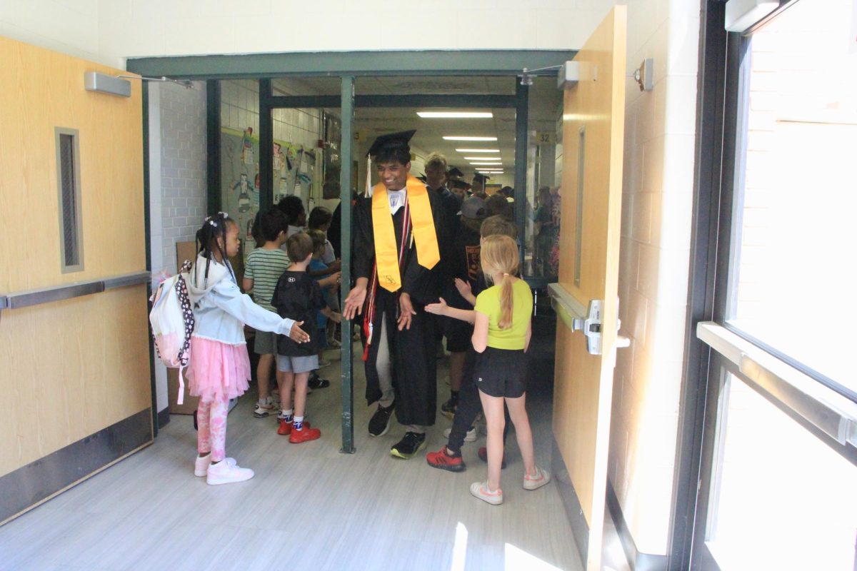 Senior, Akilesh Rajan, high-fives elementary schoolers at his visit at Ellisville Elementary.