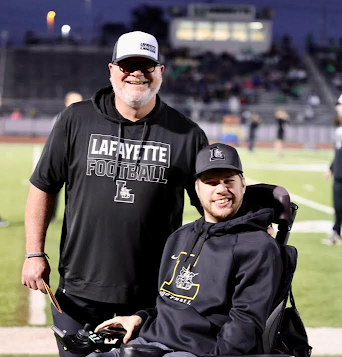 Coach Boyd Manne and his son, Ryan, pose for a picture on the sideline.