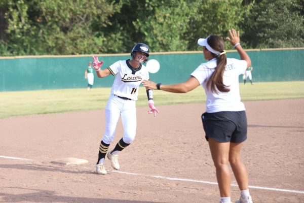 With her hand in the air, junior batter Sidney Vogt gets ready to high five her coach on a run to home-plate. Vogt hit a grand slam this game to lead the Lancers to a 16-1 blowout against St. Joe, Sept. 2.